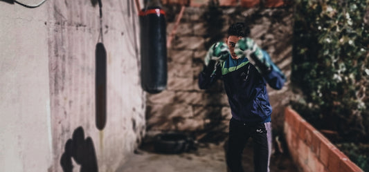 man in blue jacket and black pants standing beside black and red heavy bag