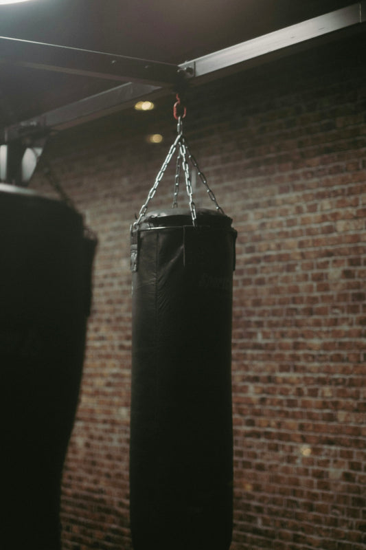 a pair of black boxing gloves hanging from a chain
