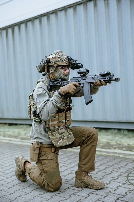 A man kneeling down with a rifle in his hand