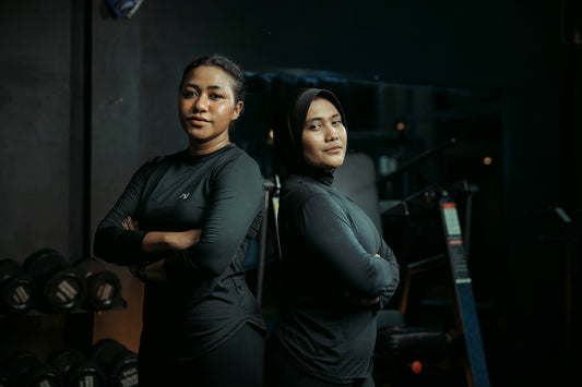 Two women stand confidently at a gym.
